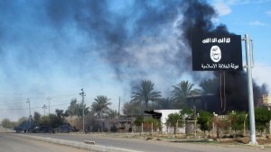 Smoke raises behind an Islamic State flag after Iraqi security forces and Shiite fighters took control of Saadiya in Diyala province from Islamist State militants, November 24, 2014. Iraqi forces said on Sunday they retook two towns north of Baghdad from Islamic State fighters, driving them from strongholds they had held for months and clearing a main road from the capital to Iran. There was no independent confirmation that the army, Shi'ite militia and Kurdish peshmerga forces had completely retaken Jalawla and Saadiya, about 115 km (70 miles) northeast of Baghdad. Many residents fled the violence long ago. At least 23 peshmerga and militia fighters were killed and dozens were wounded in Sunday's fighting, medical and army sources said. REUTERS/Stringer (IRAQ - Tags: CIVIL UNREST CONFLICT MILITARY TPX IMAGES OF THE DAY) - RTR4FED5